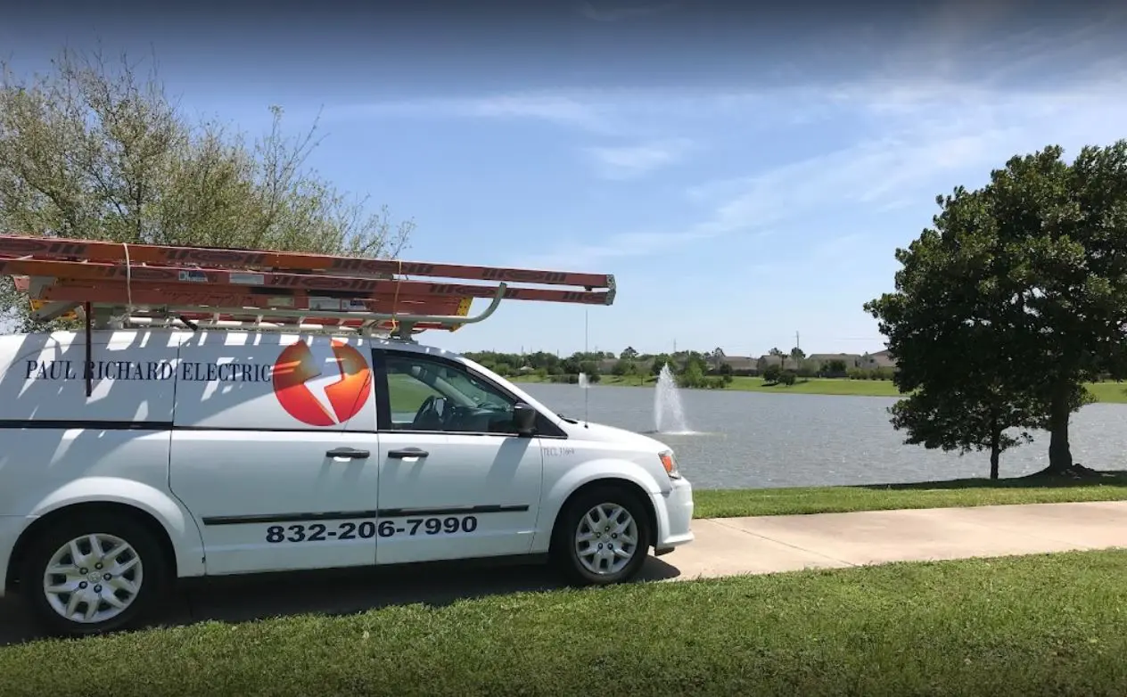 A van parked on the grass near some water