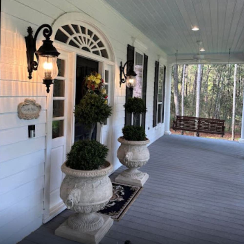 A porch with two large white urns and a door.